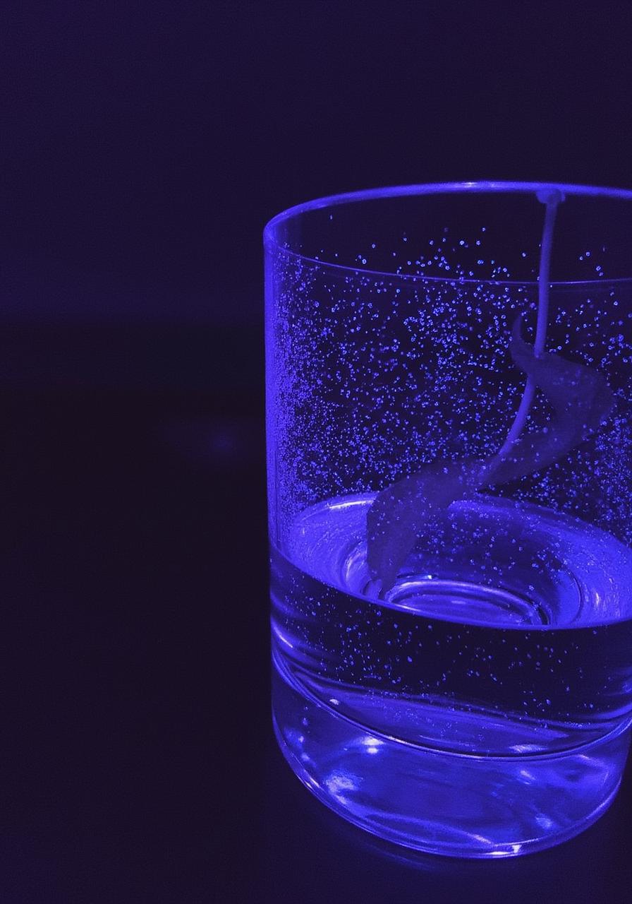 Deep violet glass of water with biophoton light particles drifting upward